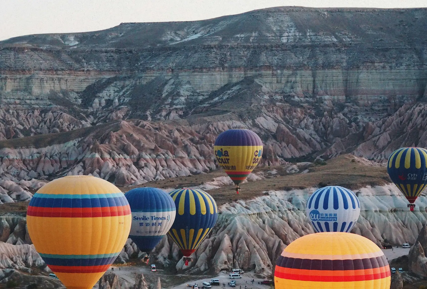Globos aerostáticos de colores sobrevolando los valles rocosos de Capadocia al amanecer