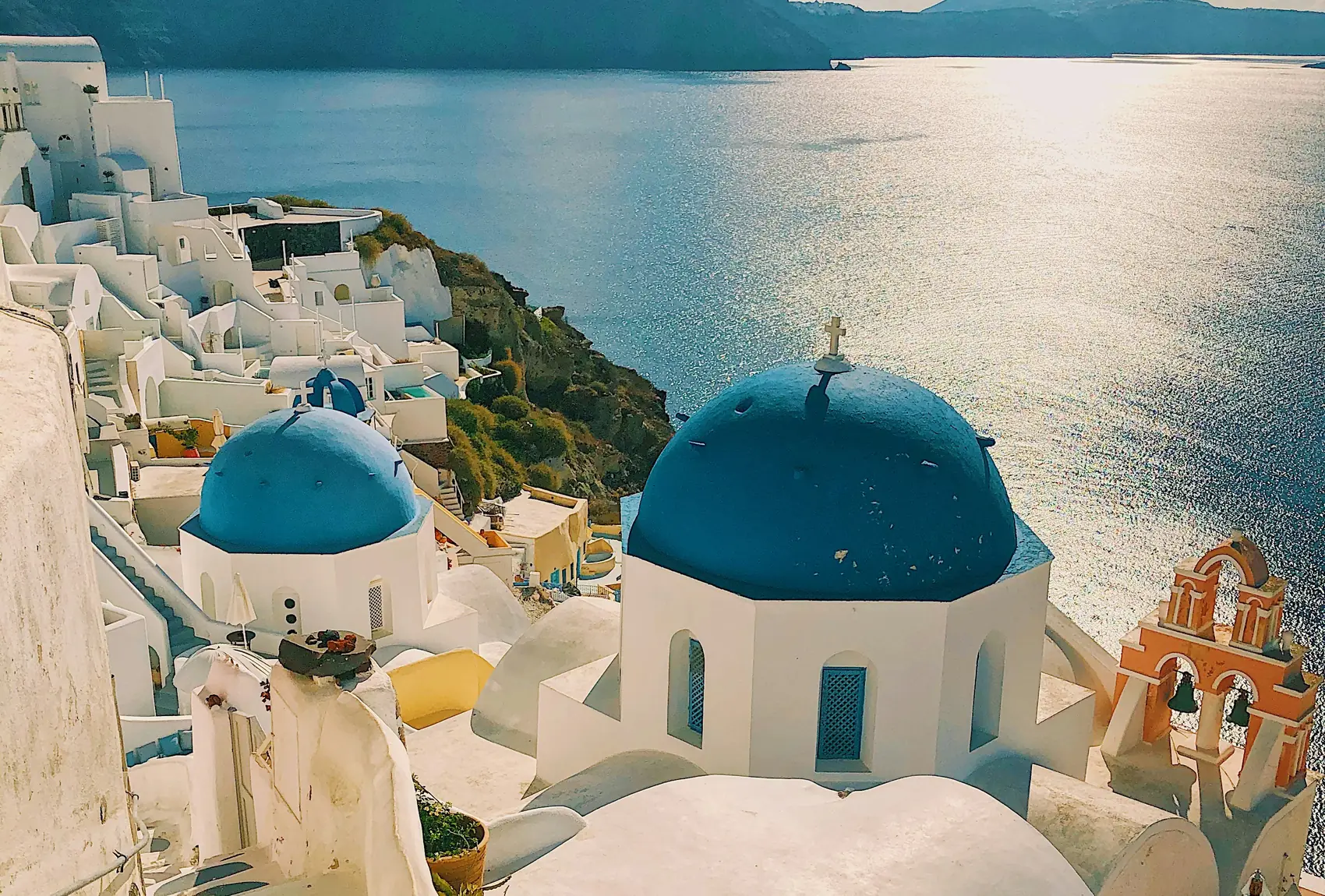 Cúpulas azules de una iglesia en Oia, Santorini, frente al mar Egeo al atardecer