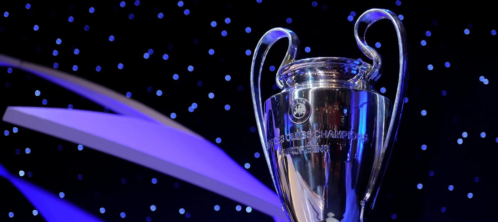 El trofeo de la UEFA Champions League iluminado sobre un fondo azul oscuro