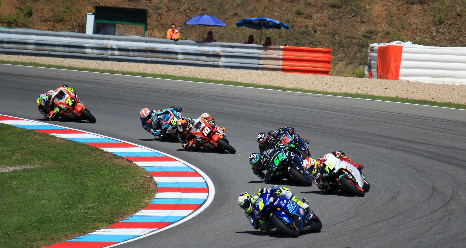Pelotón de Moto GP entrando en curva sobre el piano rojo y azul del circuito de Brno