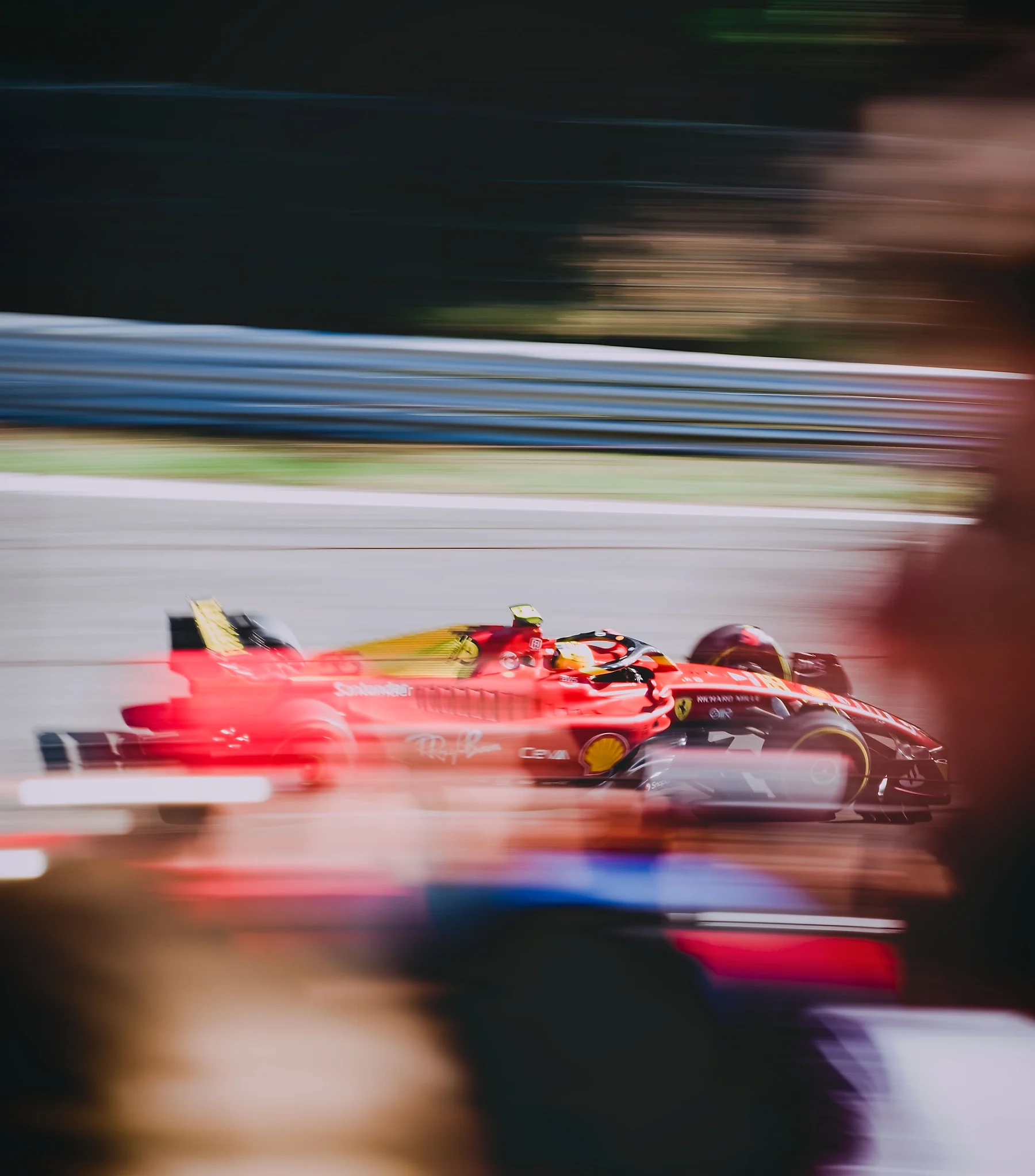 Monoplaza de Fórmula 1 de Ferrari a toda velocidad, fotografiado con barrido de cámara: el coche nítido y el circuito convertido en líneas de movimiento