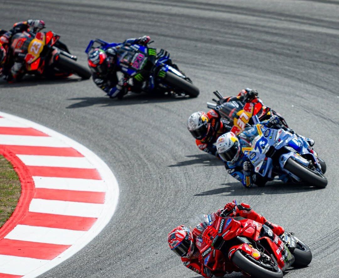 Pelotón de Moto GP inclinado en una curva, con la Ducati roja al frente